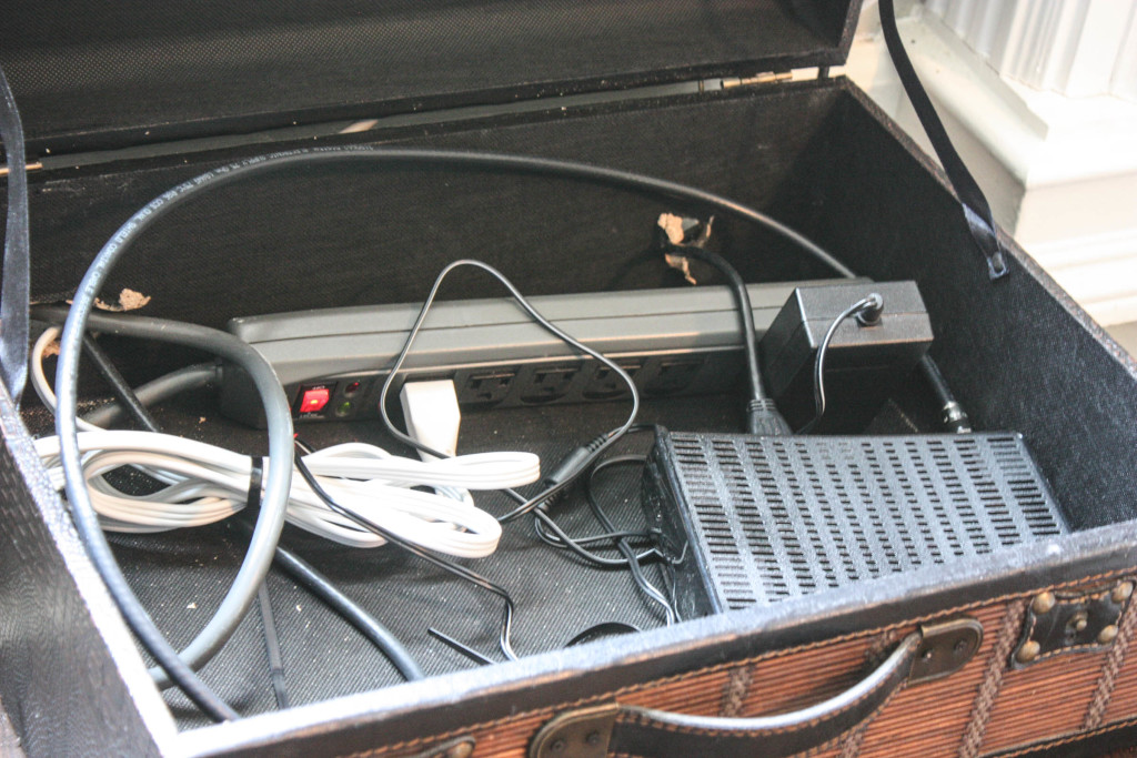 Suitcase holding satellite receiver and wires. Hole was cut into the back so that the cords would fit through.