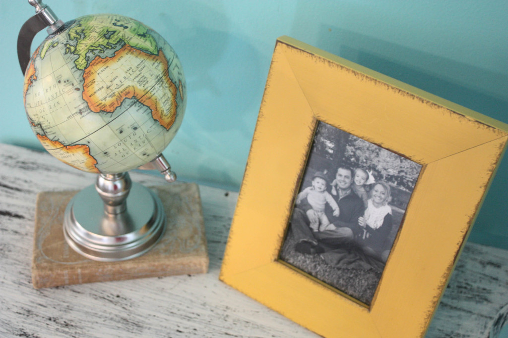 Old book, frame and globe on distressed half table