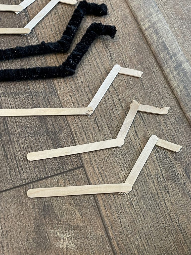 break popsicle sticks to shape of spider legs