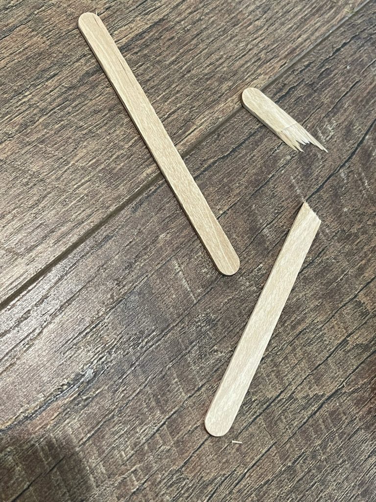 break popsicle sticks to shape of spider legs