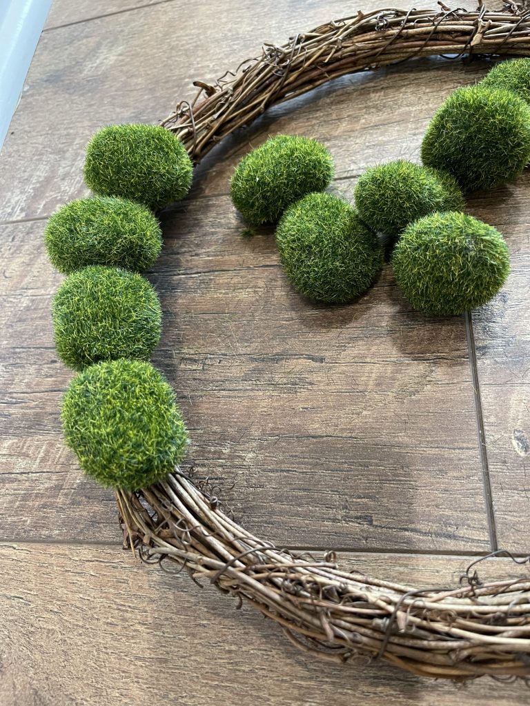 hot glue the moss balls onto the grapevine wreath