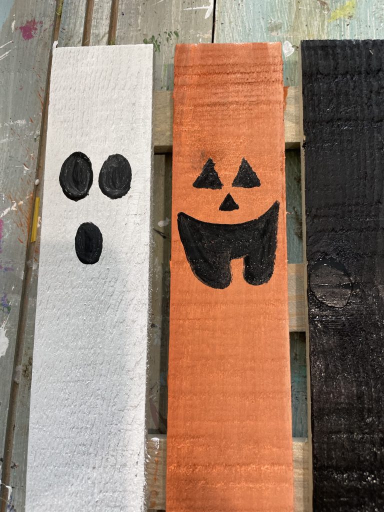 paint the pumpkin face on the orange slat