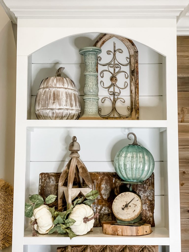 built in shelving styled with natural elements including wooden lanter, vintage scale, glass pumpkin, wooden pumpkin