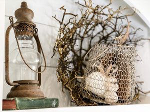 vintage lantern on top of hymnal book, beside netted vase with pumpkins