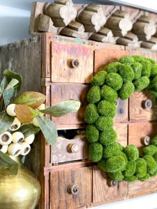 close up of green moss wreath on antique drawer shelving