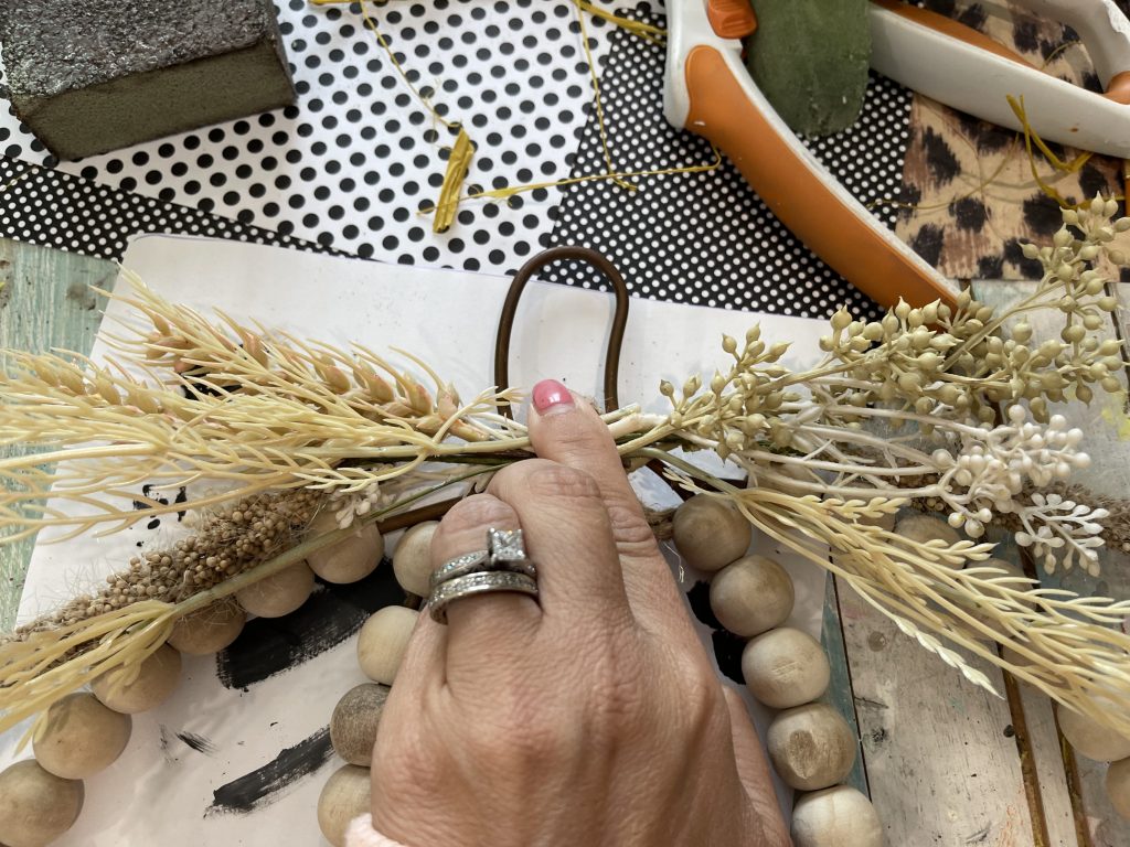 process picture of the pick being placed on the beaded pumpkin sign
